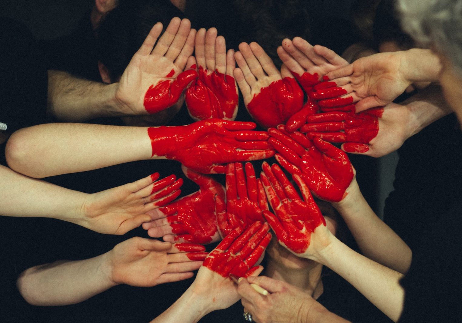 hands formed together with red heart paint